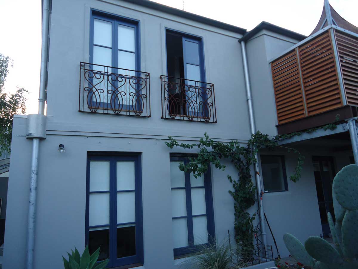Rendered two-storey townhouse exterior with navy windows, iron balconettes